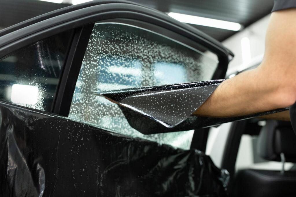 Window tint being applied to a car window by the Karzilla team in Edmonton Window tint being applied to a car window by the Karzilla team in Edmonton