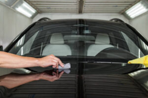 The process of applying a nano-ceramic coating on the car's hood by a male worker with a sponge and special chemical composition to protect the paint on the body from scratches, chips and damage.