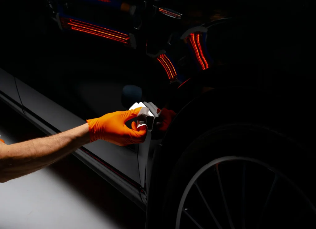 Edmonton technician applying ceramic coating to car hood beside traditional wax for comparison