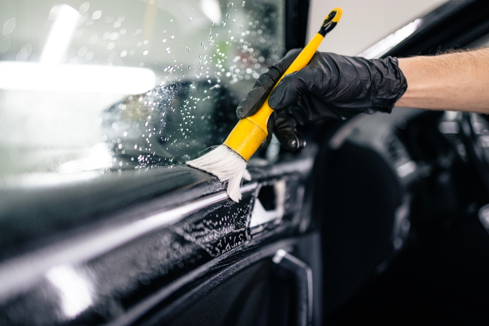 Professional car interior detailing with soft brush cleaning door trim in Edmonton